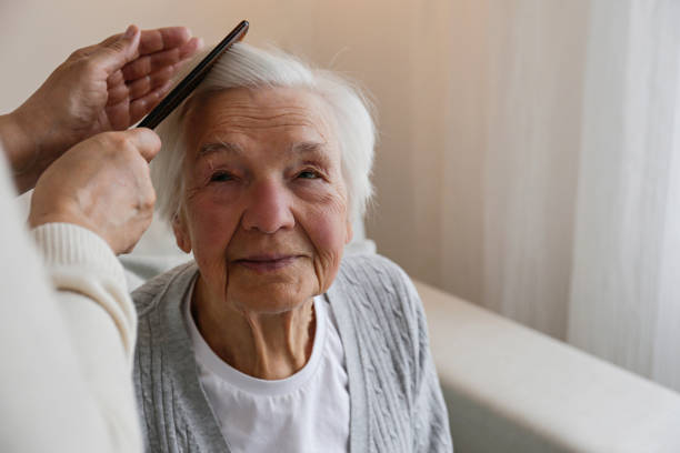 Professional caregiver providing gentle hair care to senior client at home